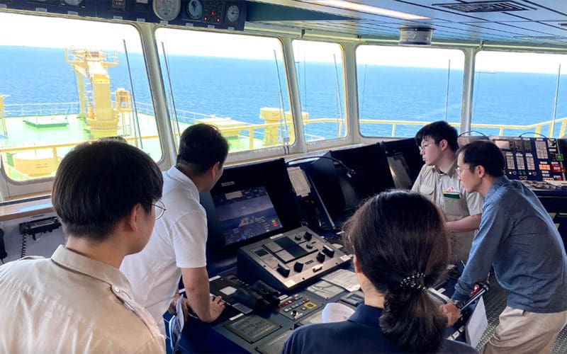 Captain and crewmembers observe the operation of the HiNAS AI nav system aboard Prism Courage.
