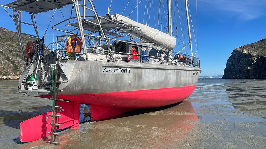 The expedition vessel, ArcticEarth sitting upright in a muddy cove.