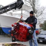 A newly-rebuilt diesel engine is hoisted into its waiting vessel. Diesel engines are renowned for their low rpm torque.