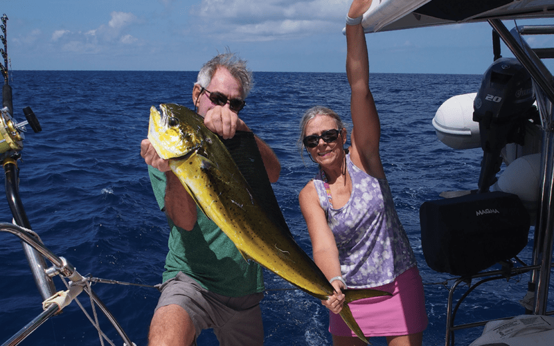 Stephen and Dawn Bell grasp a mahi-mahi they caught while underway on Pilar.