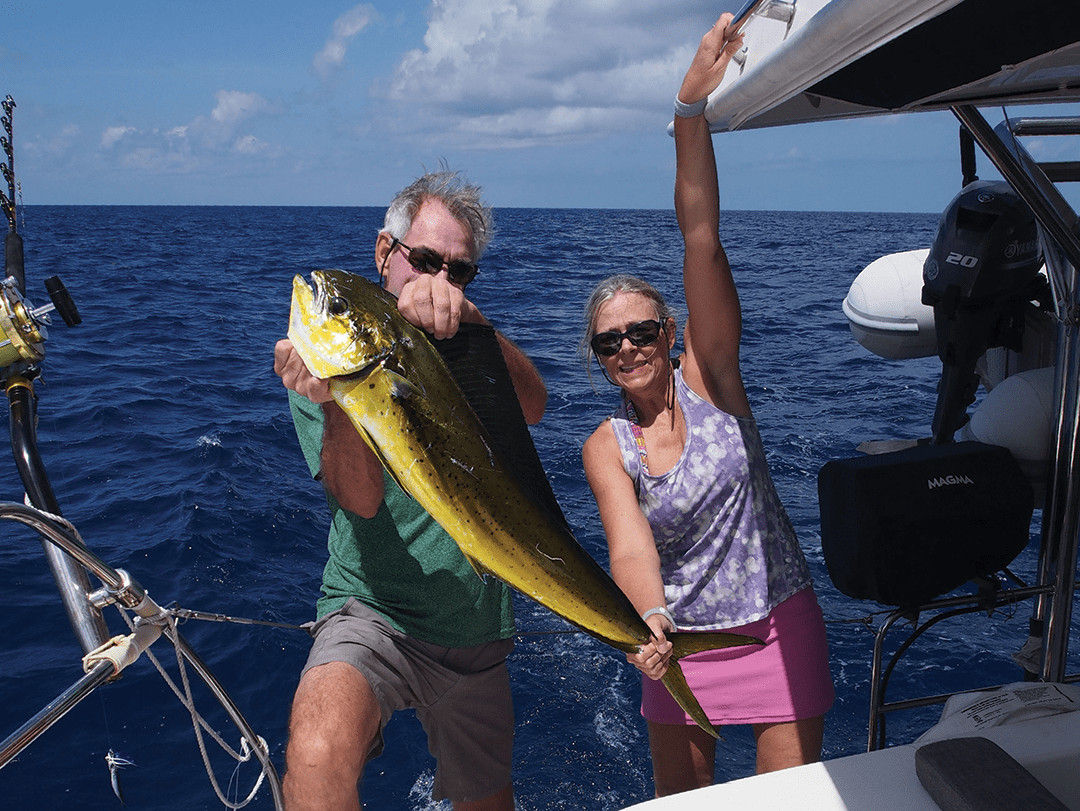 Stephen and Dawn Bell grasp a mahi-mahi they caught while underway on Pilar.