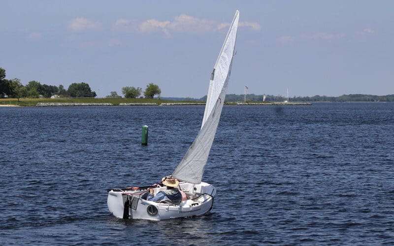 A gaff-rigged Portland Pudgy calmly sails to windward in a light breeze.