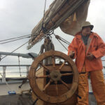 The author at the helm of the classic 131-foot schooner, Harvey Gamage.